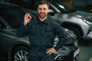 Repairman in, uniform, is standing in the garage with cars photo