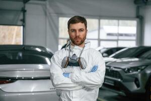 Portrait ,of, professional painter with mask that is standing in the garage with cars photo