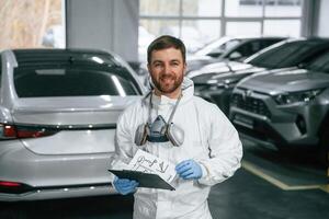 Positive facial, expression. Car painter is standing in the garage with documents in hands photo
