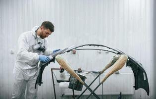 Unfinished, part... Repairman is working with carcass of the car in the garage photo