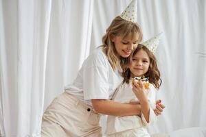 Celebrating birthday, in hats. Mother,, with ,daughter are at home together photo