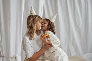 In festive hats, celebrating birthday. Mother with daughter are at home together photo