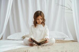 Reading the book. Cute little girl is at home photo