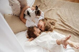 Dog pet is with them.,, Mother with daughter are at home together photo