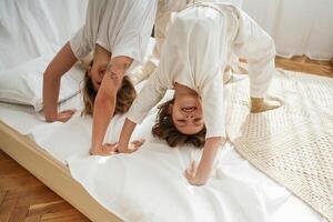 Playing in bed, standing ,on ,hands and legs. Mother with daughter are at home together, photo