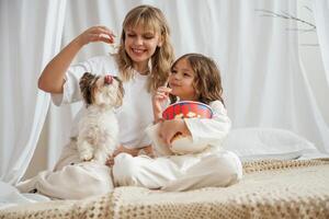 Watching movie ,with popcorn and dog. Mother with daughter are at home together photo