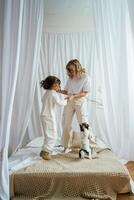 Standing ,on the bed, with dog. Mother ,with daughter are at home together photo