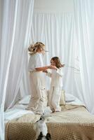 Standing, on the bed, with dog. Mother with daughter are at home together photo