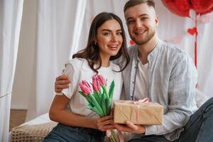 Gift box in hands, celebrating holiday. Young couple are together,, at, home photo