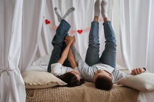 Lying down on the bed. Young,, couple are together at home photo