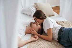 On the, bed, lying down and smiling. Young couple are together at home photo