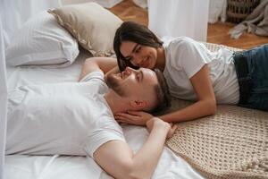 On ,the ,,bed, lying down and smiling. Young couple are together at home photo