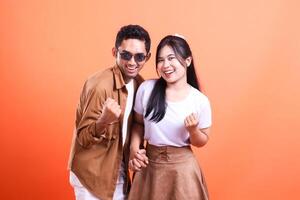 a pair of adult lovers happy expression success where the man stands and the woman faces the camera romantically. isolated on orange background photo