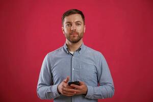 Black smartphone,, in hands. Man is standing against background in the studio photo