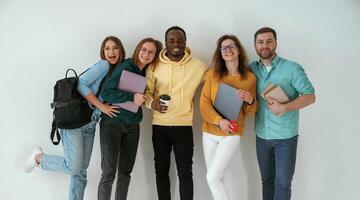 Smiling, looking forward. Group of young people are standing against white background photo