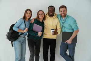 Smiling,, looking, forward. Group of young people are standing against white background photo