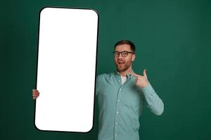 With massive smartphone with empty white color. Man is standing against background in the studio photo