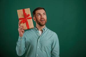 Conception of holidays, with gift box... Man is standing against background in the studio photo