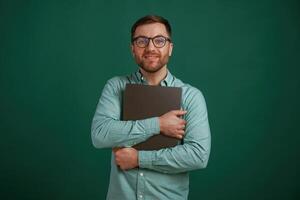 Silver colored laptop i,,n hands. Man is standing against background in the studio photo