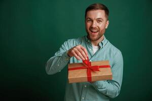 Little gift box in hands. Man is, standing against background in the studio photo