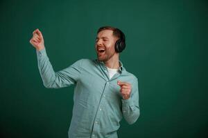 Smiling, enjoying music.. Man is standing against background in the studio photo