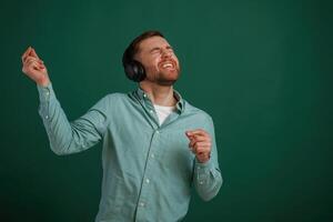 Smiling, enjoying music. Man is standing, against background in the studio photo