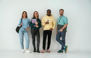 Looking forward. Group of ,young, people are standing against white background photo