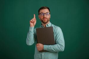 Silver, colored laptop in hands. Man is standing against background in the studio photo