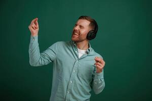 Smiling, enjoying ,music. Man, is standing against background in the studio photo
