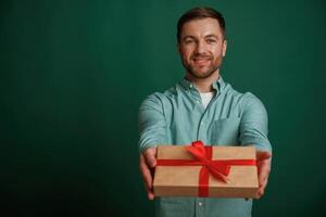 Conception of holidays,, with gift box. Man is standing against background in the studio photo