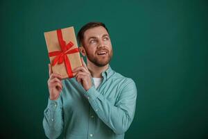 Conception of, holidays, with gift box. Man is standing against background in the studio photo