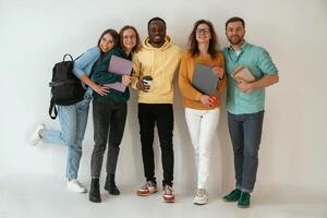 Smiling,, looking forward. Group of young people are standing against white background photo