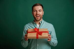 Little gift ,box in hands. Man is standing against background in the studio photo