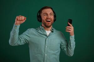 Smiling,, enjoying music. Man is standing against background in the studio photo