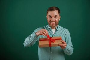 Conception,of holidays, with gift box. Man is standing against background in the studio photo