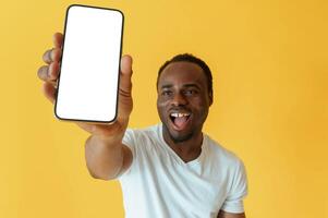 Empty display of smartphone, holding. Black man is in the studio against yellow background. photo