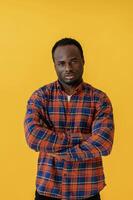 Standing, and ,,posing. Black man is in the studio against yellow background photo
