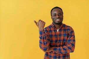 Showing to the side for ,,copy ,space. Black man is in the studio against yellow background photo
