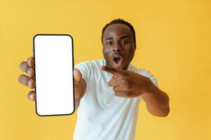 Empty, display ,,of smartphone, holding. Black man is in the studio against yellow background photo