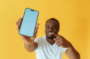 Empty display, of ,smartphone, holding. Black man is in the studio against yellow background photo