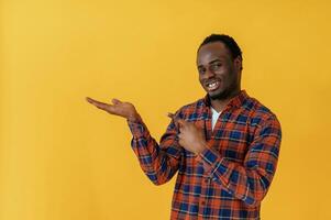 Showing to the side for copy space.. Black man is in the studio against yellow background photo