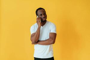 Making a call. Black man is in the studio against yellow background photo