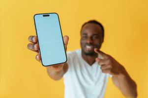 Empty, display of smartphone, holding. Black man is in the studio against yellow background photo