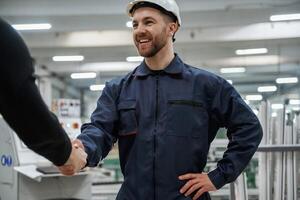 Doing handshake. Man on the factory is making deal with other person,, photo