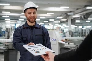 Giving the document with plan. Man on the factory is making deal with other person. photo