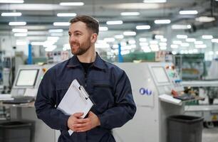 Standing and smiling. Factory worker is indoors with hard ,hat photo