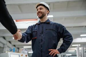 Doing, handshake. Man,, on t,he factory is making deal with other person photo