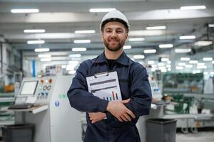 Happy ,,with results, holding graphs... Factory worker is indoors with hard hat photo