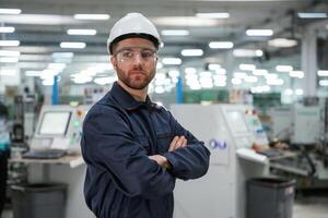 Posing, with,, arms ,crossed. Factory worker is indoors with hard hat photo