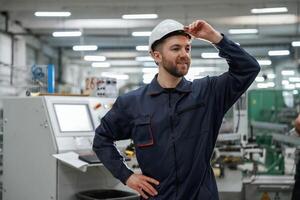 Employee, is looking far,, away. Factory worker is indoors with hard hat photo
